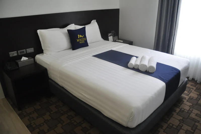 SOP 學員宿舍房型，配有大床、床頭燈與 Mezzo Hotel 寢具